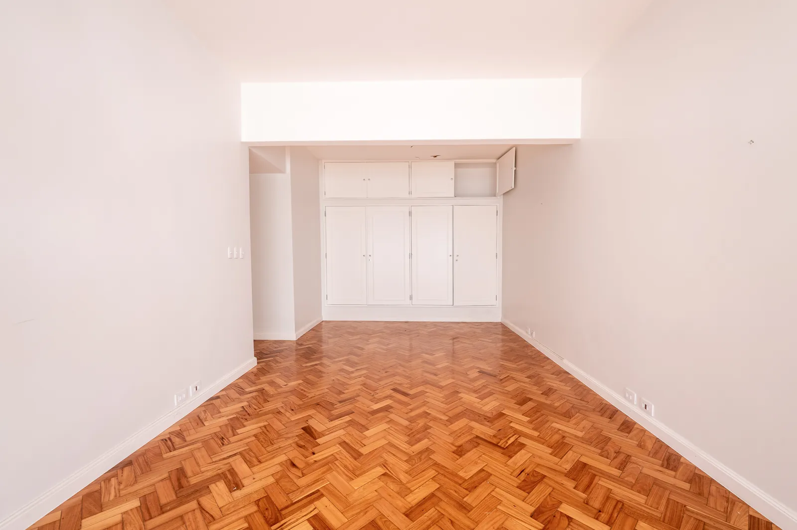 A bedroom with fitted wardrobes and herringbone parquet
