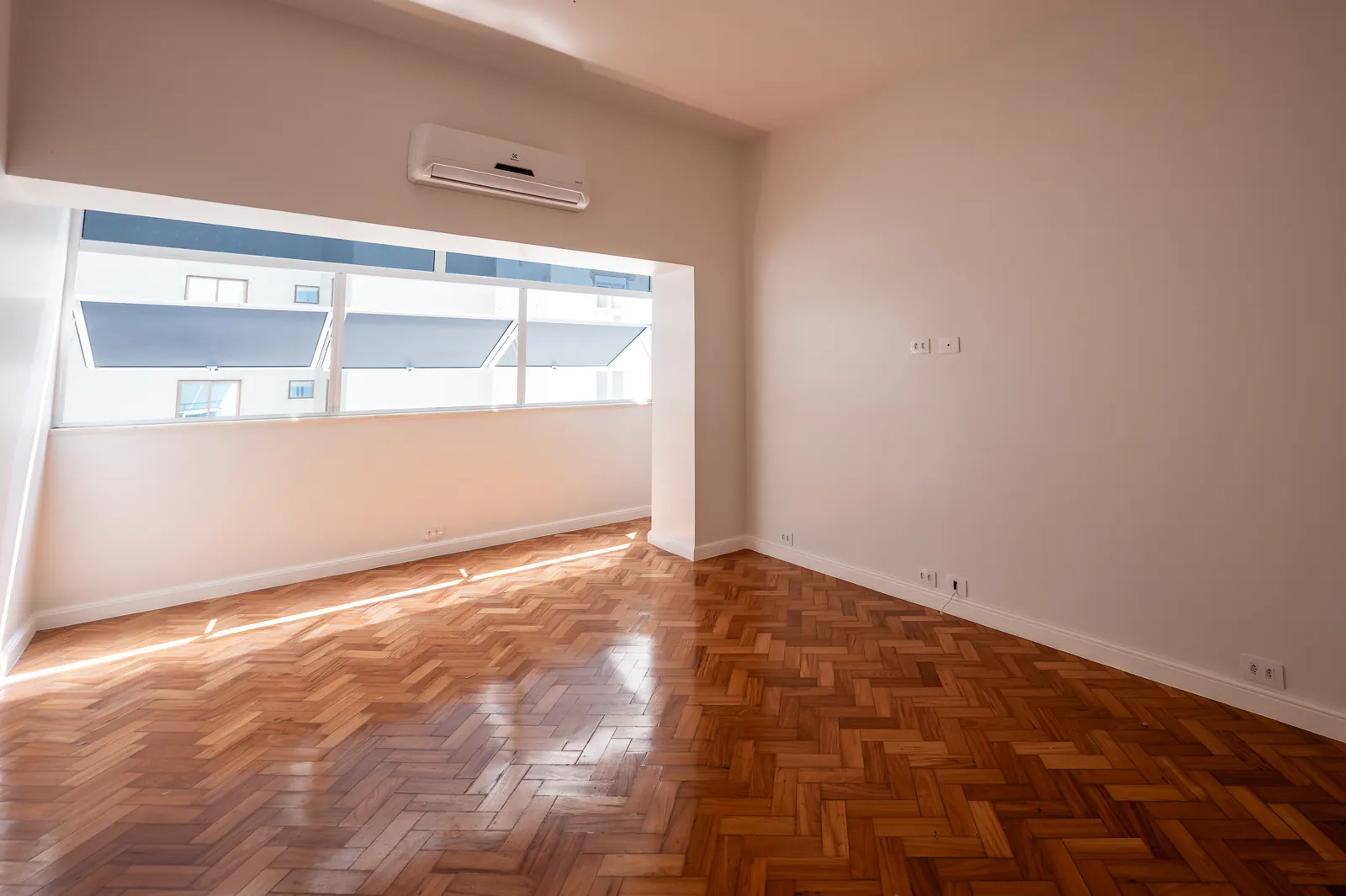 A light room with air conditioning, a wide window and parquet